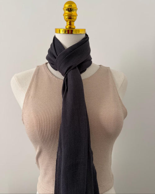 Mannequin wearing a beige ribbed sweater and dark scarf against a plain background