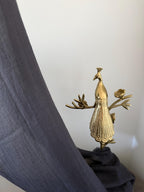 Gold peacock decorative item on a gray fabric