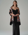 Woman wearing a floral shawl over a black outfit on a gray background