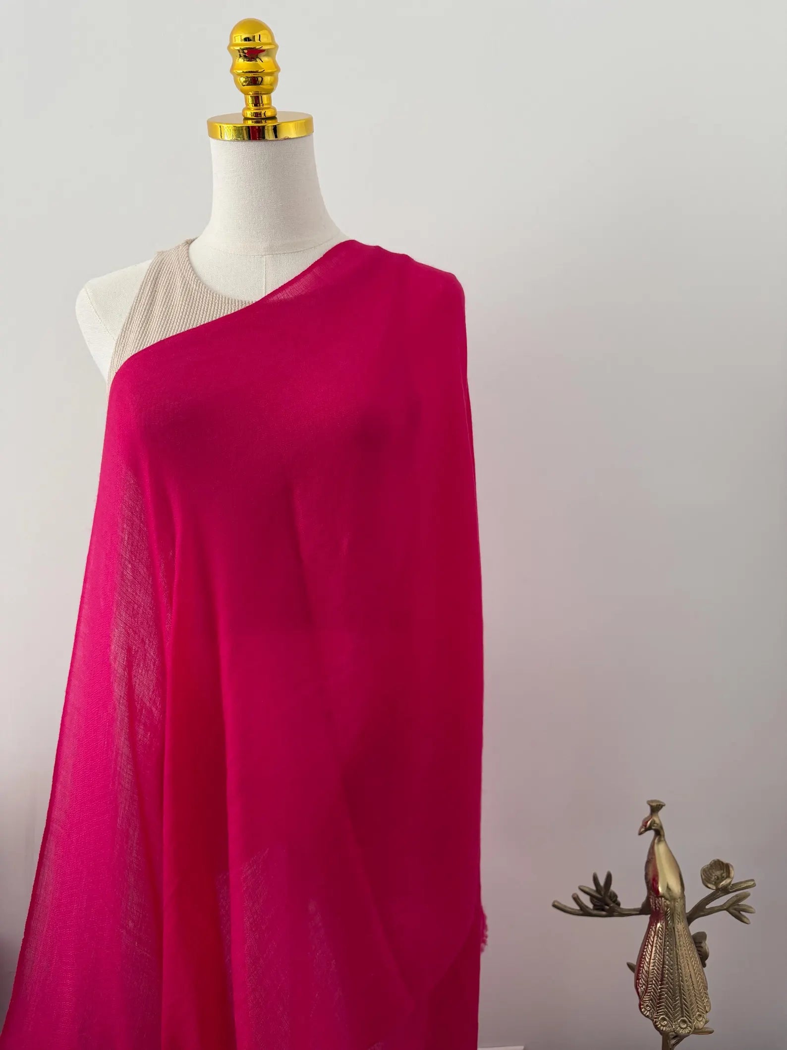 Mannequin wearing a bright pink one-shoulder dress against a plain background