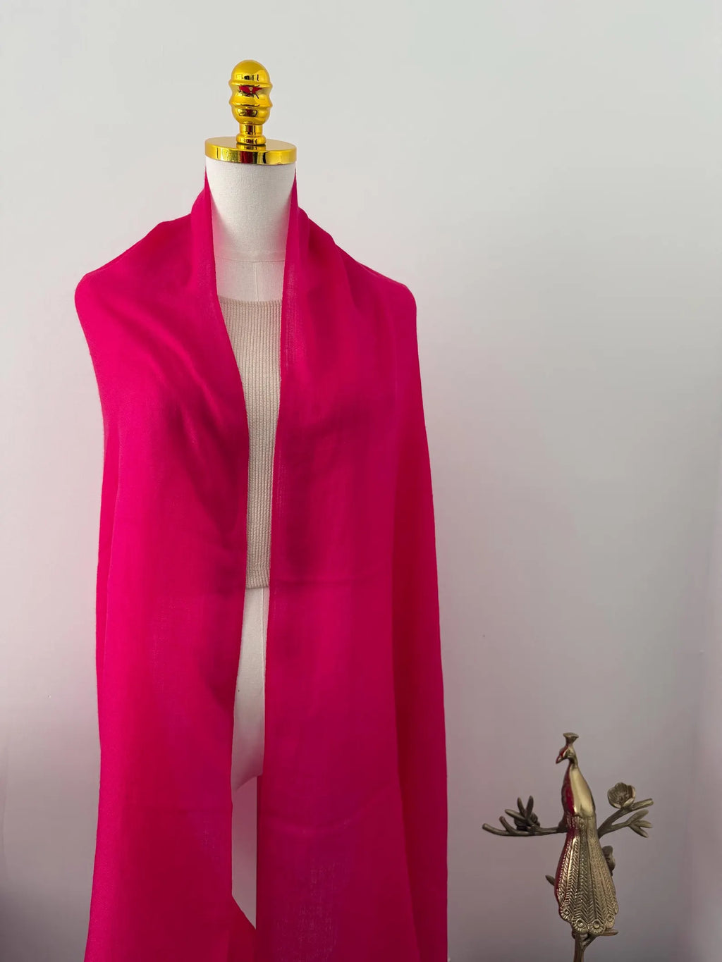 Mannequin wearing a bright pink scarf with a plain background