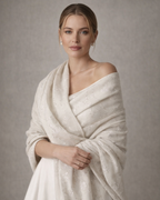 Woman wearing a white shawl against a plain background