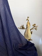 Gold peacock decorative item on a blue fabric background