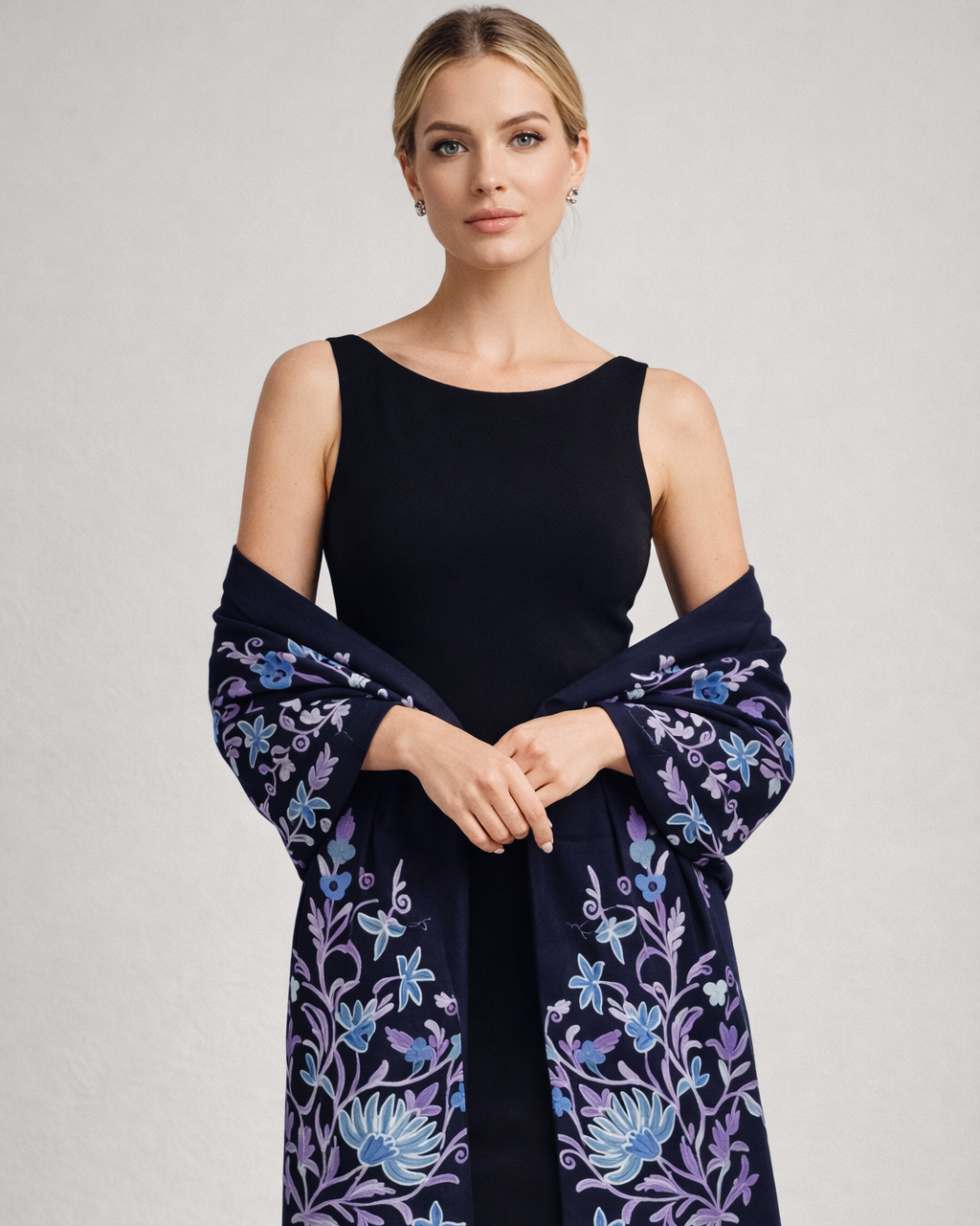 Woman wearing a black dress with a navy blue embroidered shawl on a light gray background
