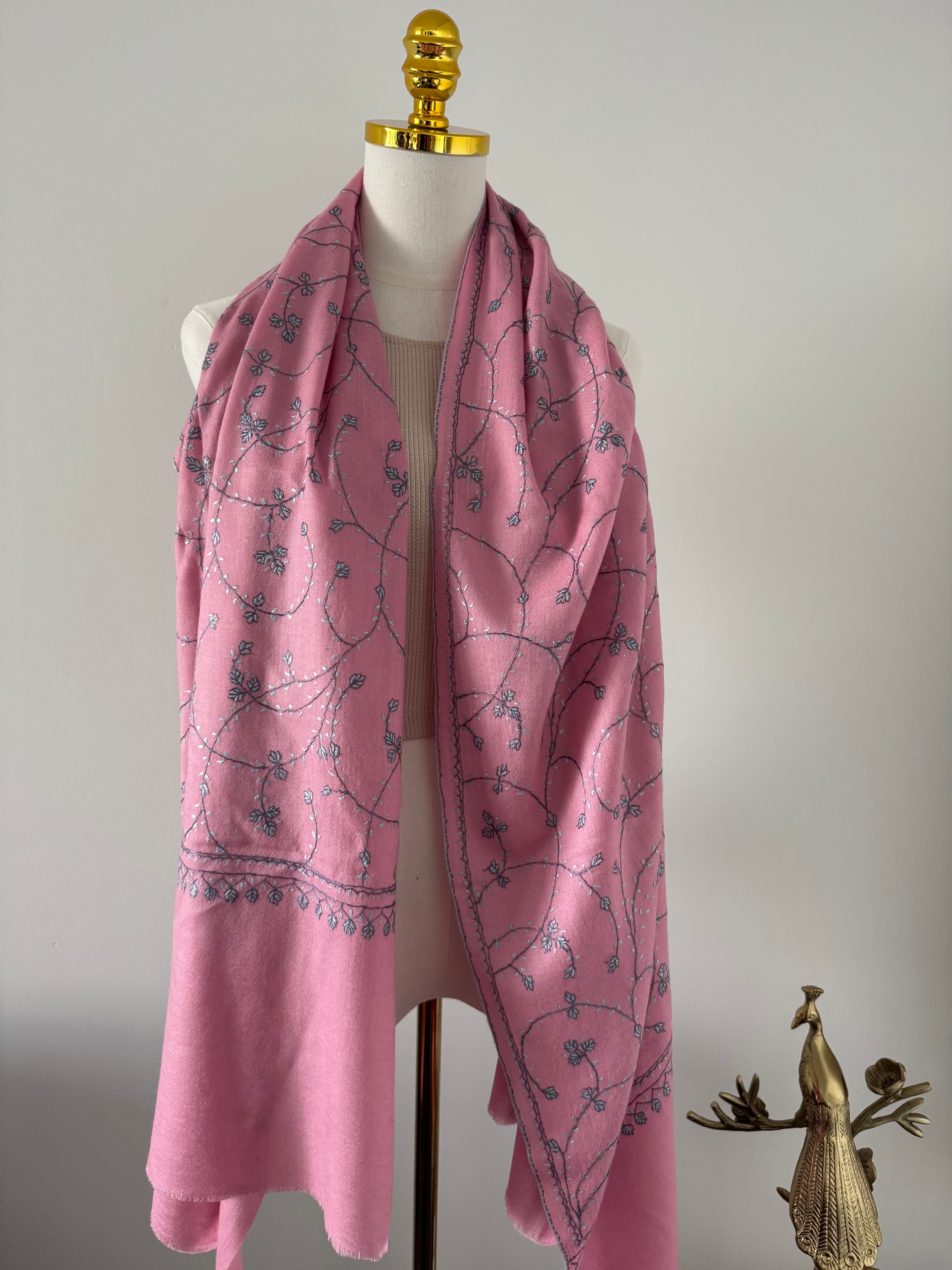 Pink scarf with light blue floral pattern on a mannequin against a plain background