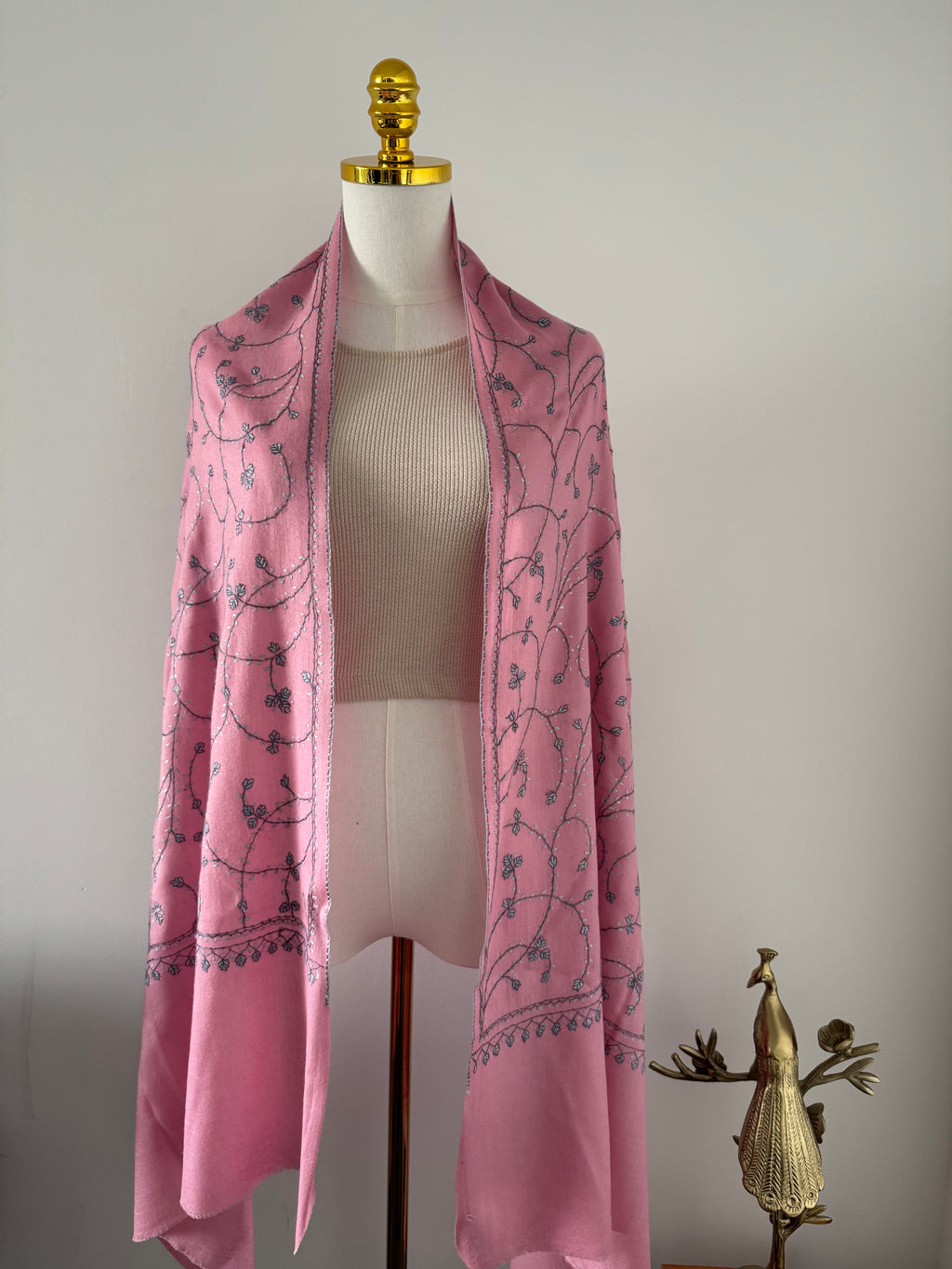 Pink fabric with black floral pattern on a white mannequin against a plain background