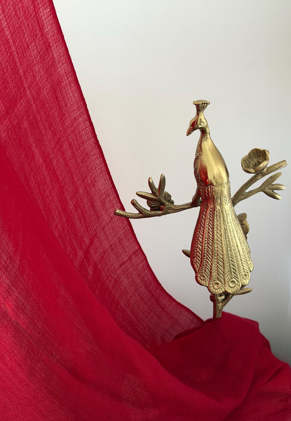 Gold peacock decorative item on a red fabric background