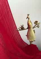 Gold peacock decorative item on a red fabric background