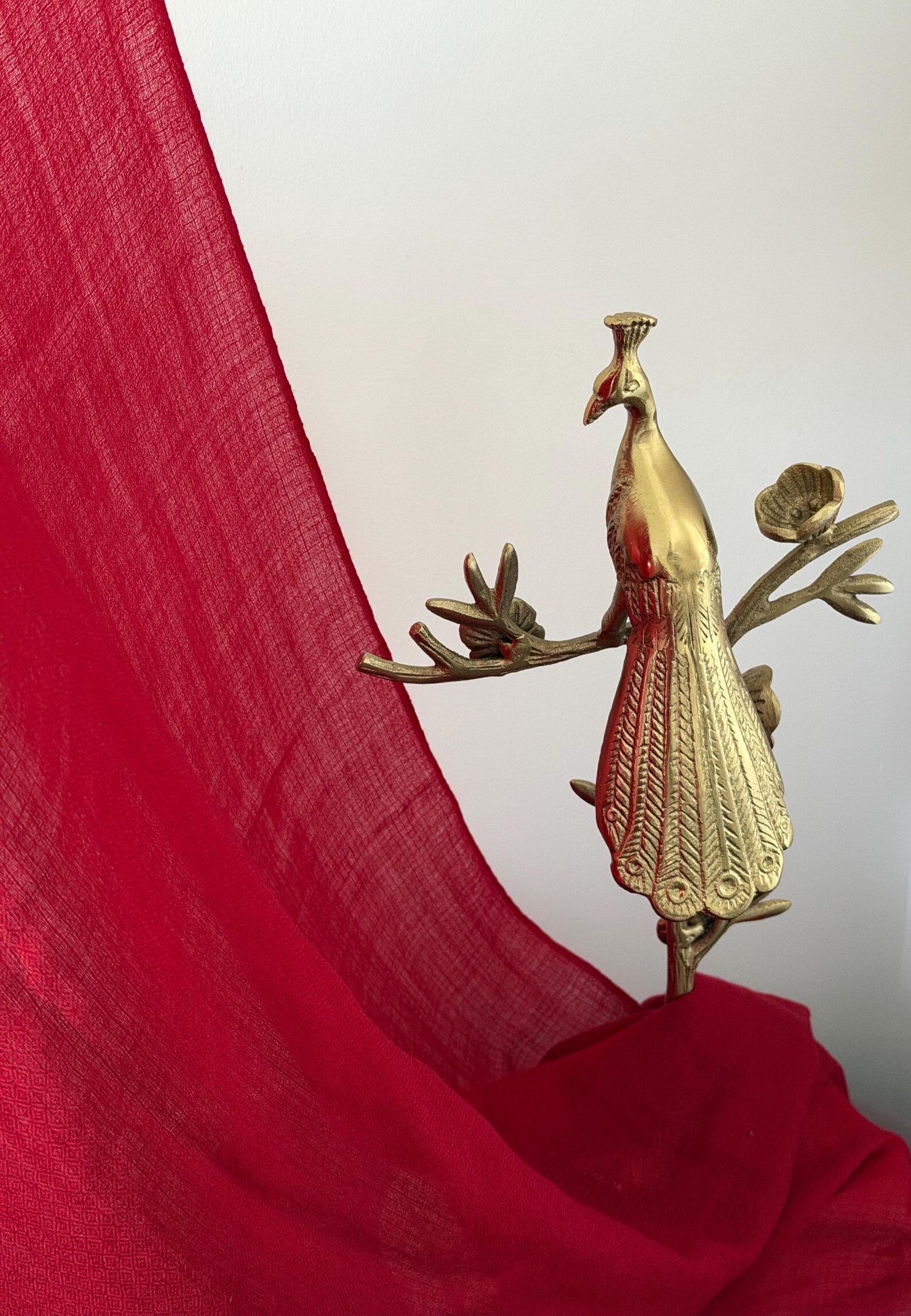 Gold peacock decorative item on a red fabric background