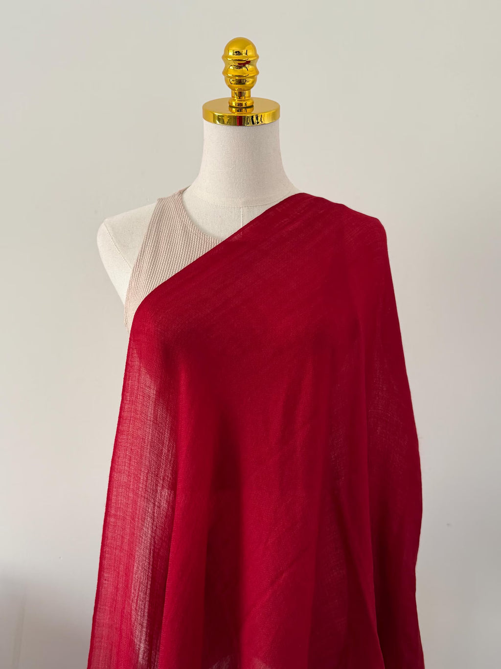 Red fabric draped over a mannequin on a plain background