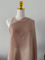 Mannequin wearing a brown draped fabric against a gray background