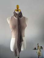 Mannequin wearing a beige sleeveless top and brown scarf against a plain background