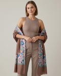Woman wearing a brown outfit with a patterned shawl on a plain background