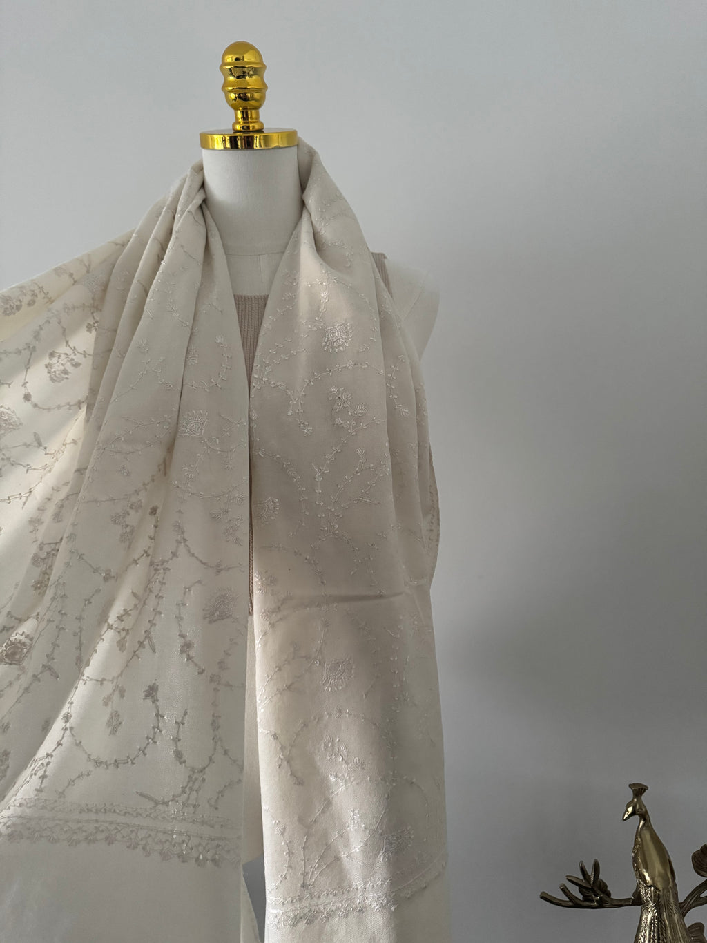 Close-up of a decorative white fabric embroidery on a plain background