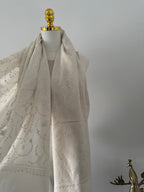 Close-up of a decorative white fabric embroidery on a plain background