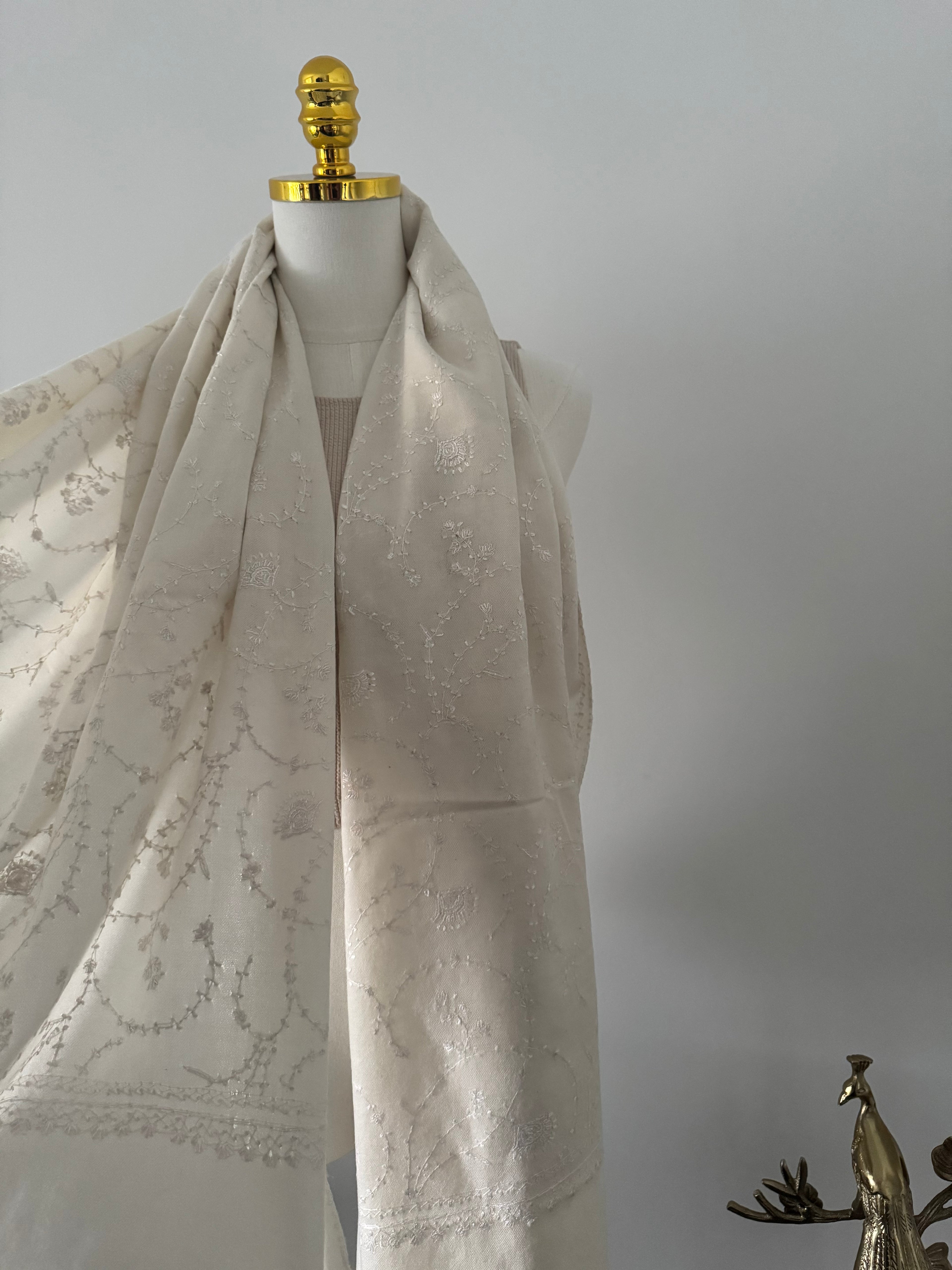 Close-up of a decorative white fabric embroidery on a plain background