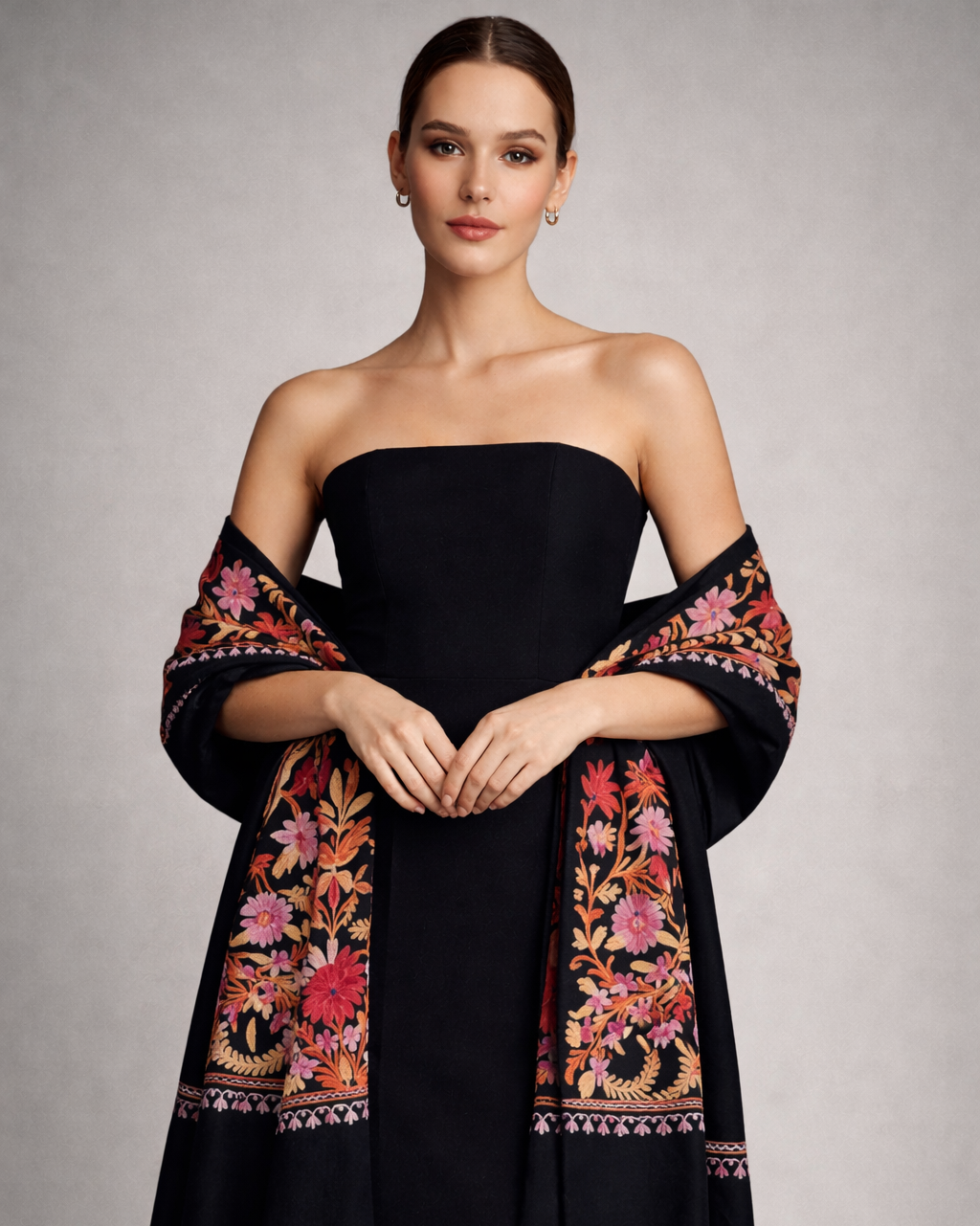 Woman wearing a black dress with floral embroidery on a gray background