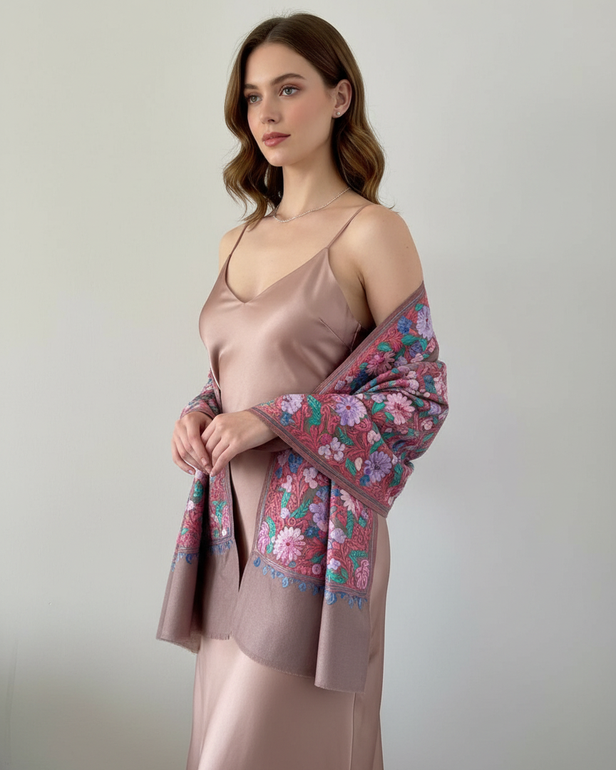 Woman wearing a satin slip dress with floral shawl against a plain background